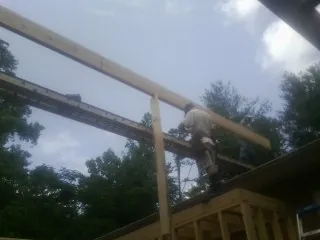 Carpenter setting a ridge beam over a new addition frame — Ice Dam Removal by Roofing Brothers in Linesville
