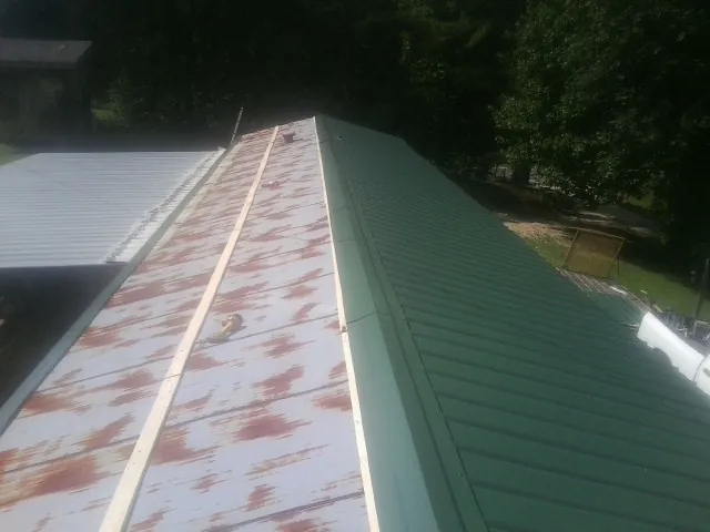 Old rusted panels beside newly installed green metal roofing — Wind Damage Roof Repair by Roofing Brothers in Linesville