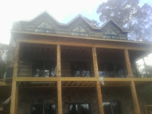 Dormers and porch framing on a large log home under construction — Roof Coating work by our crew in Linesville