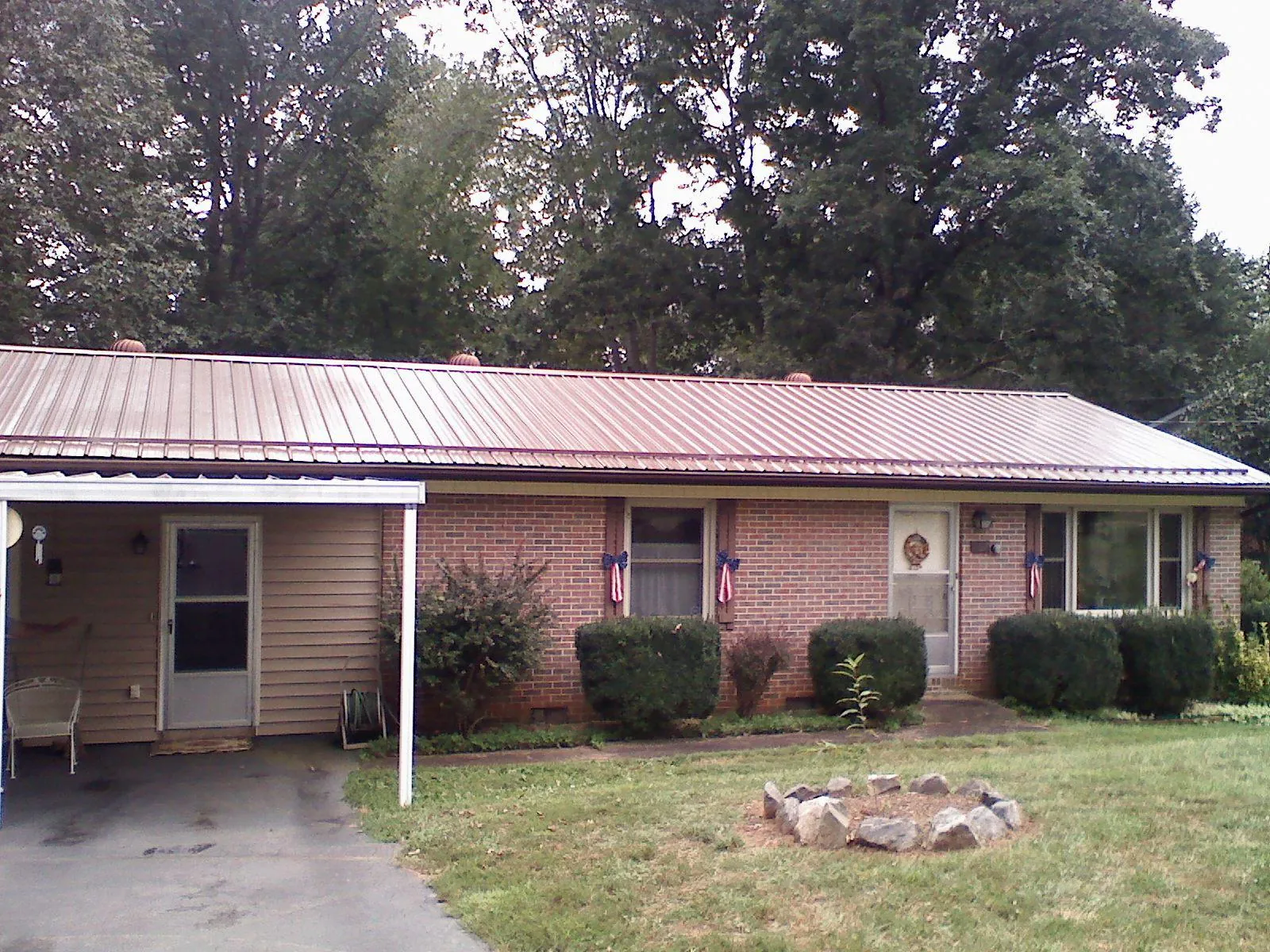 Bronze metal roof and carport on a brick ranch home — Roof Repair work by our crew in Linesville
