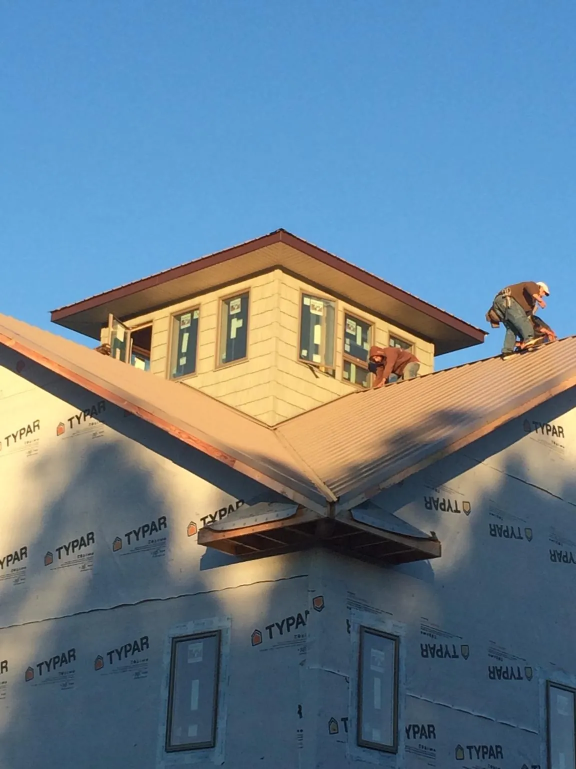 Roofers working around a rooftop cupola on a new metal roof at sunset — Roof Waterproofing in Linesville by Roofing Brothers